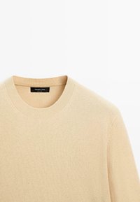 Béžový pletený svetr s kulatým výstřihem, se žebrovanými okraji a měkkou texturou. Štítek nese nápis "Massimo Dutti."