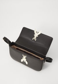Borsa in pelle nera con una texture liscia, caratterizzata da accessori metallici a forma d'insetto. L'interno è foderato con un tessuto decorato.