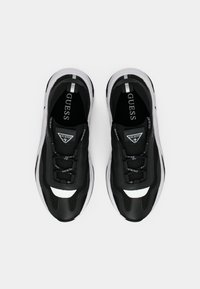 Black athletic shoes with a textured upper, white accents, and rubber soles. Features a logo on the tongue and laces for secure fit.