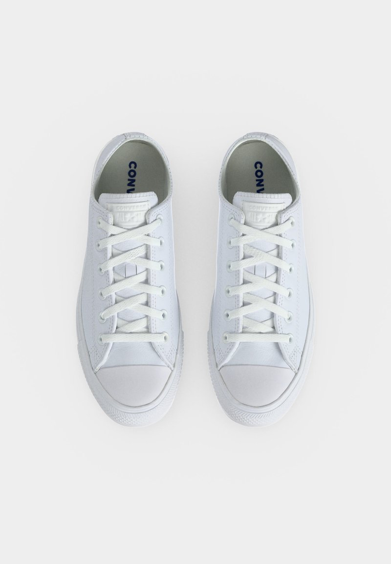 Paar saubere weiße Low-Top Converse-Sneaker mit weißen Schnürsenkeln auf einem weißen Hintergrund, von oben betrachtet.