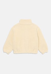 Krémový fleece svetr s vysokým límcem, elastickými manžetami a texturovaným, měkkým povrchem. Má volný střih a nařasený lem.
