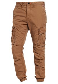 Brązowe spodnie cargo z bawełny, z elastycznymi mankietami, wieloma kieszeniami bocznymi oraz zapięciem na guzik w pomarańczowym kolorze.