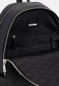 Zaino in pelle nera con un'esterno testurizzato, chiusura a doppia cerniera e un interno foderato con un motivo di branding ripetuto.