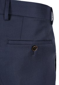 Navyblaue Hose aus strukturiertem Stoff mit einer Seitentasche und einem braunen Knopf. Der Bund ist mit integrierten Gürtelschlaufen versehen.