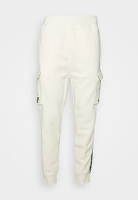 Light cream sweatpants with elastic waistband, cargo pockets on each side, cuffed ankles, and side stripes featuring black accents.