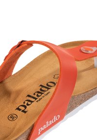 Sandal in pelle arancione con soletta in sughero. Presenta una fascia superiore testurizzata, una fibbia regolabile e una suola in gomma bianca. Visibile il marchio "Palado".