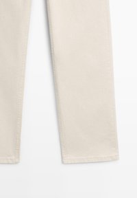 Parte inferiore di pantaloni color crema a gamba dritta con cuciture laterali visibili e dettagli sull'orlo, su sfondo bianco.