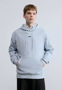 Ανοιχτό μπλε φούτερ με κουκούλα από μαλακό ύφασμα, με μπροστινή τσέπη, ρυθμιζόμενο σκοινί στο καπάκι και μικρό μαύρο λογότυπο "BOSS" στο στήθος.