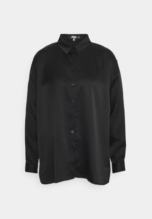 Chemise noire à manches longues avec col, finition satinée lisse et boutons visibles sur le devant, sur fond blanc.