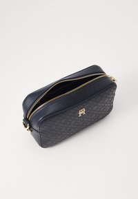 Borsa cosmetica in pelle blu marino con pattern testurizzato, zip dorata e dettaglio del logo. Forma rettangolare con apertura a zip e base piatta.