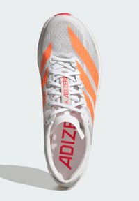 Scarpa da atletica bianca con strisce arancioni, caratterizzata da una tomaia testurizzata e lacci. All'interno è visibile la scritta "ADIZERO" in rosso su un plantare grigio.