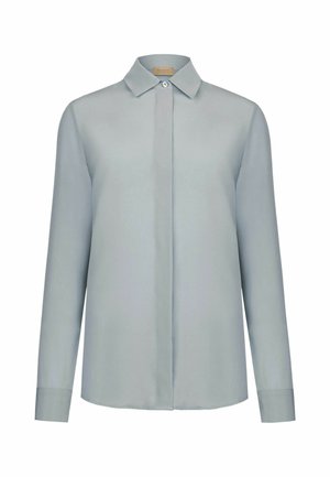 Blouse pour femme à manches longues gris clair avec col pointu, patte de boutonnage cachée, et un seul bouton visible en haut.