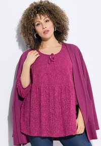 Top viola texturizzato con vita arricciata e dettaglio a fiocco alla scollatura, sovrapposto a un cardigan aperto abbinato.