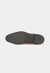 Leather shoe sole with a sleek design. Color features a dark grey bottom and brown accents. Smooth texture with defined edge stitching.