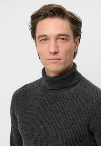 Dunkelgrauer Rollkragenpullover aus gerippter Strickstruktur. Verfügt über ein tailliertes Design mit hohem Kragen und minimalistischem Stil.