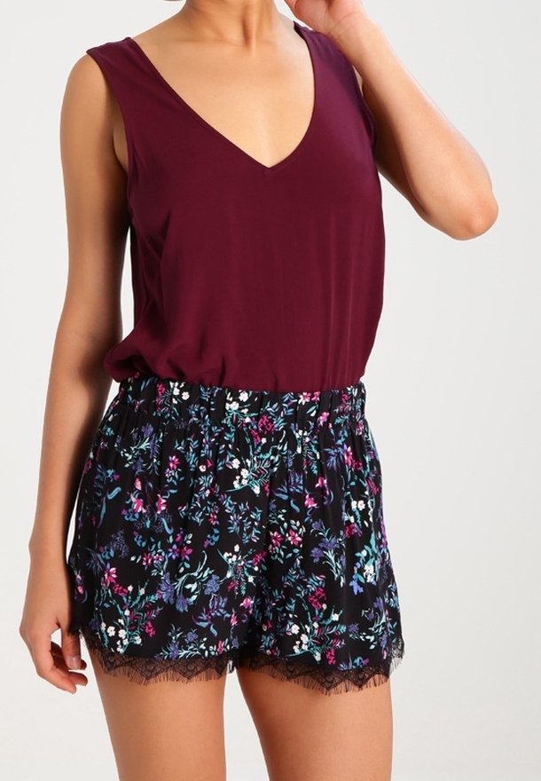 Burgundy ärmlös topp med V-ringning, kombinerad med svarta blommiga shorts med blå, rosa och vita blommor samt spetsdetaljer vid fållen.