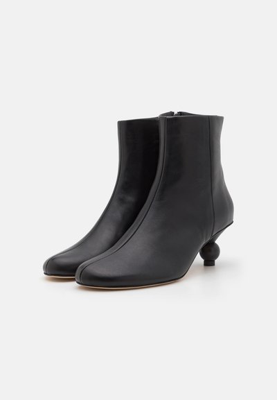 Botine din piele neagră, cu un siluet elegant, vârf ascuțit și un toc rotund unic. Dispun de un fermoar lateral pentru o îmbrăcare ușoară.