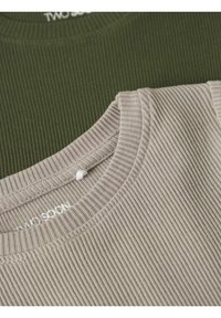 To ribbede t-shirts stablet: en i olivengrøn og den anden i lys beige. Begge har runde halsudskæringer og struktureret stof.