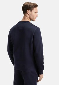 Sweatshirt bleu marine avec un col rond, tissu texturé, poignets et ourlet côtelés, et un détail de couture unique à l'arrière. Design simple.