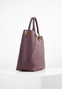 Borsa in pelle di un borgogna tenue con superficie liscia, doppi manici, dettagli in metallo dorato e una silhouette strutturata.