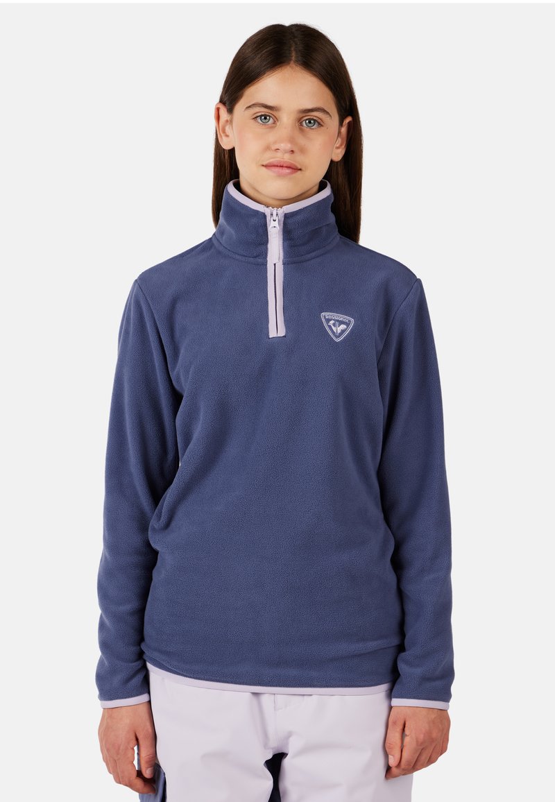 Fleece mikina v námořnické modři, s vysokým límcem, polo-zip uzavíráním a malým logem na hrudi. Měkká textura s kontrastními akcenty.