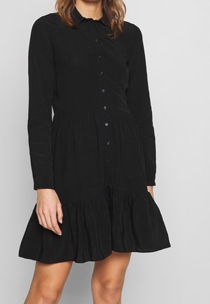 Robe noire à manches longues avec boutonnage sur le devant, taille froncée et ourlet évasé à volants. Texture lisse avec un col classique.