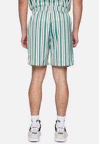 Randiga shorts i grön, vit och lila med elastisk midja. Tillverkade av ett mjukt tyg, med vertikala ränder och en avkopplad passform.