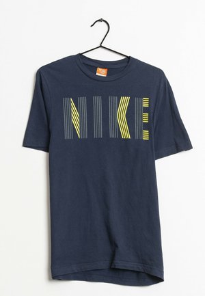 Camiseta de algodón azul marino con un diseño gráfico de la palabra "NIKE" en líneas verticales de diferentes tonos de gris y amarillo fluorescente.