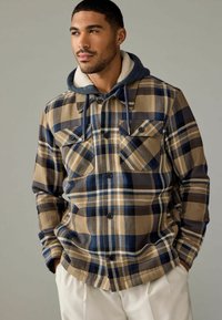 Geruite button-up shirt in beige, marineblauw en bruin, met een grijze capuchon en fleece voering. Bevat twee borstzakken en een afgeronde zoom.