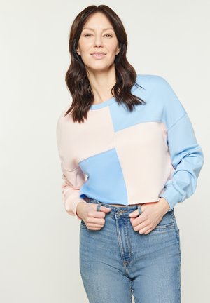 Lekkka bluza z kolorowym blokiem w pastelowych odcieniach różu i niebieskiego, z okrągłym dekoltem i luźnym krojem. Połączona z spodniami typu high-waist.