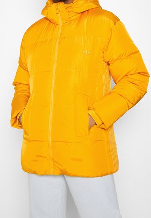 Gul puffjakke med hætte, der har en frontlynlås, sidelommer og et lille logo. Glat, blankt materiale med quiltet design.