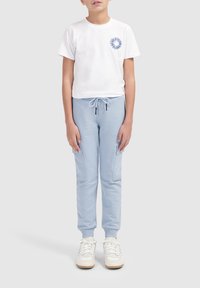 Witte T-shirt met korte mouwen met een blauwe grafische afbeelding op de borst, gecombineerd met lichtblauwe joggers met zijzakken en een koord in de taille.