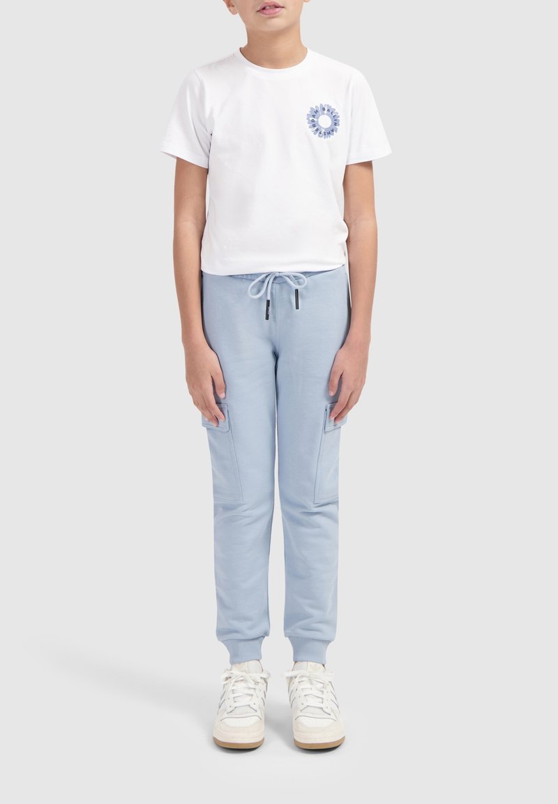 Witte T-shirt met korte mouwen met een blauwe grafische afbeelding op de borst, gecombineerd met lichtblauwe joggers met zijzakken en een koord in de taille.