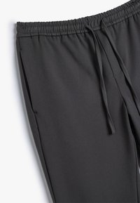 Grå, afslappede sweatpants med elastisk talje og justerbar snor, der har sidelommer og en glat, blød tekstur.