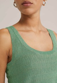 Grünes, geripptes Tanktop mit Rundhalsausschnitten und breiten Trägern, das ein strukturiertes Strickmuster und eine figurnahe Passform aufweist.