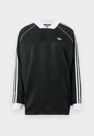 Fekete hosszú ujjú, V-nyakú póló, függőleges csíkokkal, fehér díszítésekkel, és három fehér csíkkal minden ujján. Kicsi logó a mellrészen.