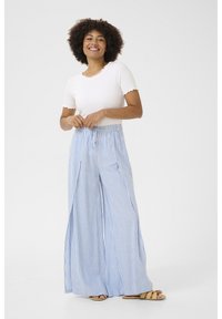 Bela rebrasta majica s valovitim robom, kombinirana s svetlo modrimi in belimi prugastimi širokimi hlačami. Hlače imajo elastični pas in žepke.