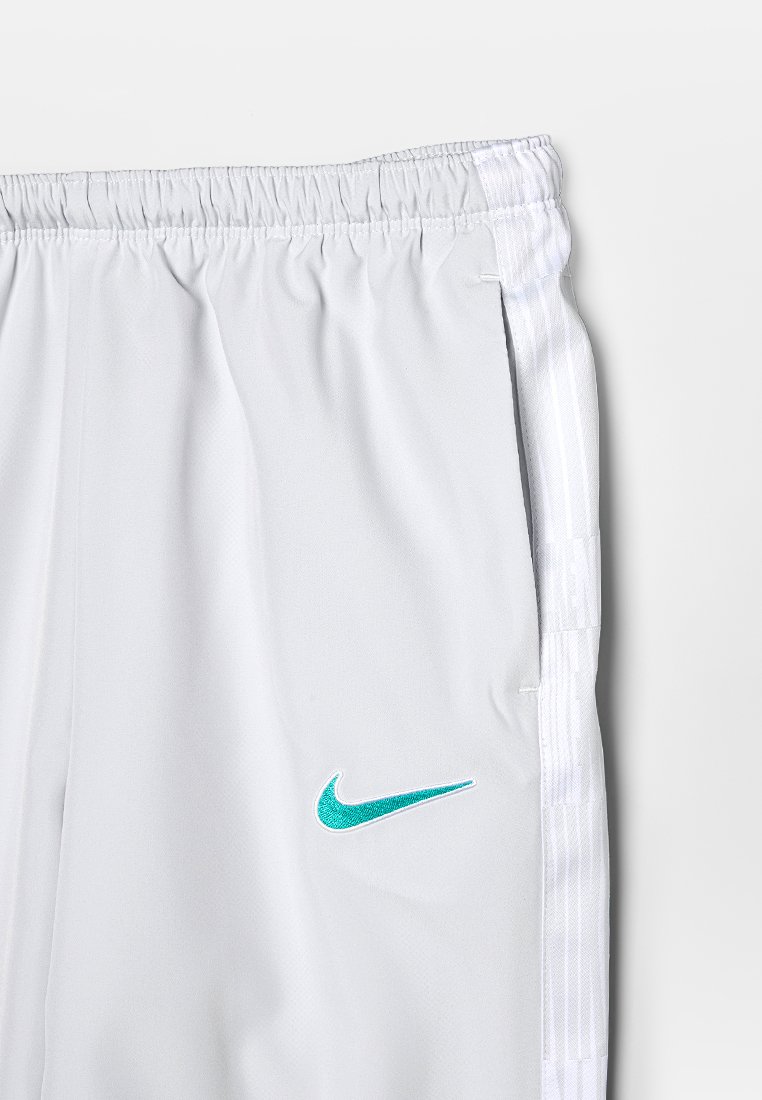 Pantaloni sportivi Nike di colore grigio chiaro con cintura elasticizzata. Presentano un logo turchese e pannelli laterali a strisce bianche per un tocco di dettaglio in più.