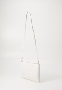 Sac en cuir blanc à bandoulière avec une texture lisse, de forme rectangulaire, une sangle ajustable, des finitions en doré et une fermeture éclair sur le dessus.