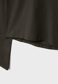 Donkerbruine t-shirt met een ontspannen pasvorm, voorzien van een afgeronde zoom en zijsplitten. Gemaakt van zachte, gladde stof met minimale stiksel details.