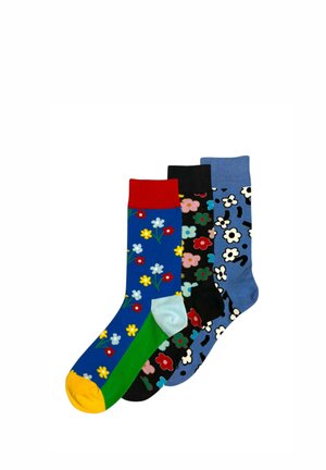 Trzy kolorowe skarpetki z kwiatowymi wzorami: niebieska z czerwonym mankietem i żółtym palcem, czarna z wielokolorowymi kwiatami oraz niebieska z białymi kwiatami.