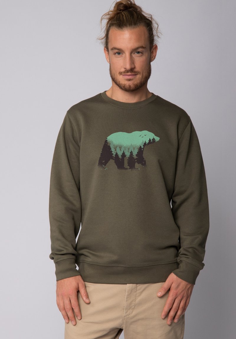 Olivegrüner Sweatshirt mit langen Ärmeln, das eine Bärensilhouette zeigt, die mit Wald- und Bergdesigns in Türkis und Dunkelgrün gefüllt ist.