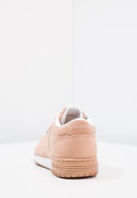 Ljusrosa mockaskor med en vit tunga och foder. Utrustad med präglat Reebok-märke på hälen och strukturerad gummisula. Rundad form.