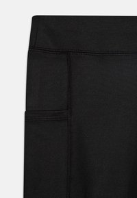 Legging noirs en matière extensible avec une taille élastique, dotés d'une poche latérale et de détails de couture renforcés.