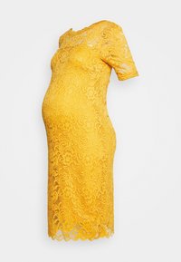 Gul spetsklänning med korta, tajta ärmar, blommönster och en böjd nederkant. Tyget har en texturerad, detaljerad design.