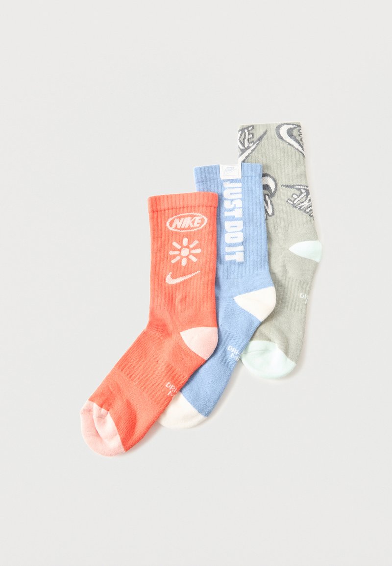 Τρία καλσόν Nike σε κοραλί, ανοιχτό μπλε και γκρι με λογότυπα και το κείμενο "JUST DO IT" στο ανοιχτό μπλε ζευγάρι, με λευκές λεπτομέρειες στα δάχτυλα και τη φτέρνα.