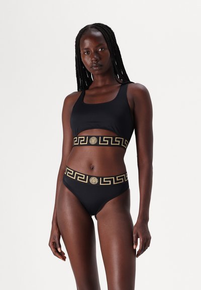 Zwart bikini-set met een sportieve top en hooggesneden broekjes, geaccentueerd met een gouden Griekse sleutelpatroon en logo op de tailleband.