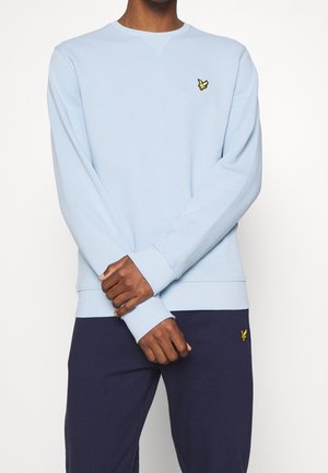 Sweatshirt bleu clair en tissu doux, avec des manches longues et un col rond. Comprend un petit logo brodé jaune sur la poitrine.