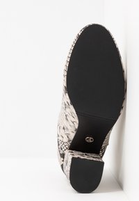 Black and white snake-print shoe with a textured surface, rounded toe, and a black rubber sole. Simple, elegant design with a modest heel.