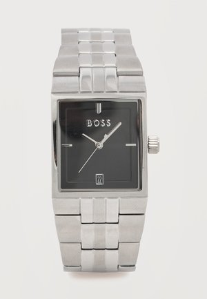 Taisnstūrveida sudraba rokas pulkstenis ar melnu ciparnīcu, sudraba stundu un minūšu rādītājiem, datuma rādītāju pie pulksteņa sešiem un "BOSS" logotipu zem pulksteņa divpadsmitiem.